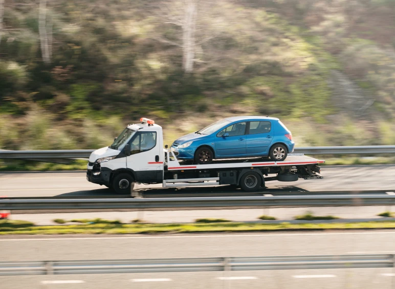 Blue car on flatbed tow truck